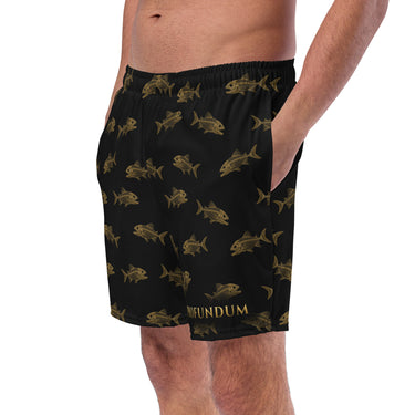 Badeshorts IN PROFUNDUM – am Model von vorne links – goldene Piranha-Skelette auf Schwarz, Schriftzug am linken Bein, powered by Nyrra-Design