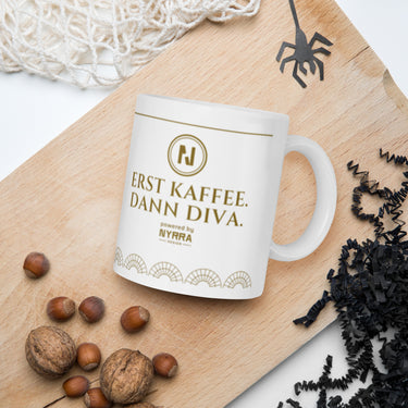 Tasse ERST KAFFEE. DANN DIVA. – im Lifestyle-Setting – weiße Glanztasse mit Dunkelgold-Medaillon und Art-déco-Fächerbordüre, powered by Nyrra-Design