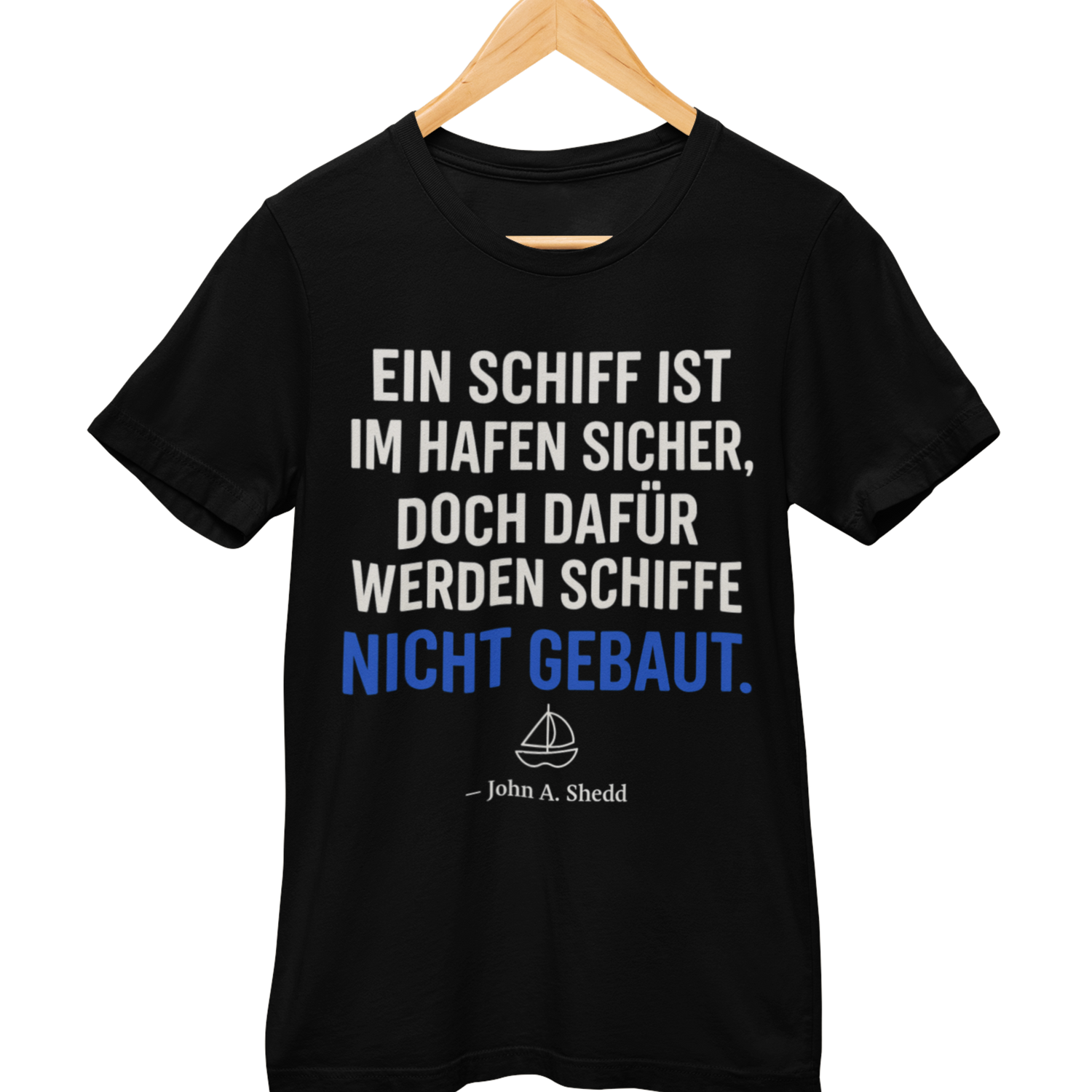 Schwarzes T-Shirt mit Zitat „Ein Schiff ist im Hafen sicher, doch dafür werden Schiffe nicht gebaut.“ in weiß-blauer Schrift, ergänzt durch ein kleines Schiffs-Icon und den Autor „John A. Shedd“ 