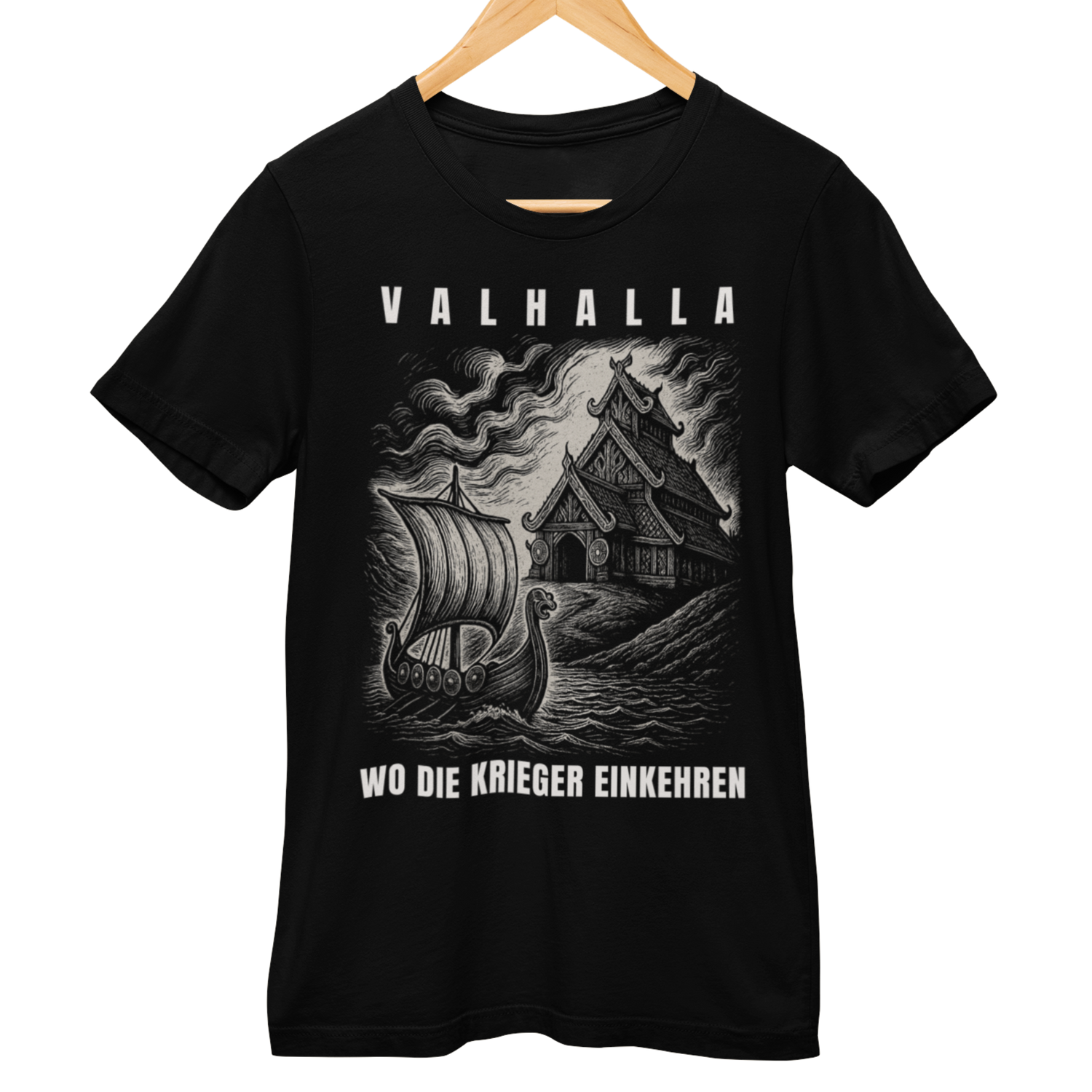 Schwarzes T-Shirt auf Holzkleiderbügel mit weißem Druck. Motiv: Wikinger-Langschiff vor einer nordischen Halle im Holzschnitt-Stil. Darüber der Text „VALHALLA“, darunter „WO DIE KRIEGER EINKEHREN“.