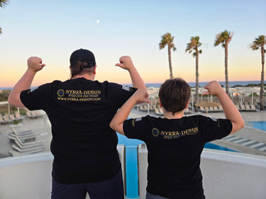 Zwei Personen in schwarzen Nyrra-Design T-Shirts mit Rücken-Print, Sonnenuntergang an einem Pool mit Palmen – Nyrra-Design Merch im Alltag