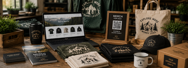 Professionelles Merch-System von Nyrra-Design mit Laptop, QR-Aufsteller, Kleidung und Merch-Produkten für Tourismus-, Event- und Erlebnisbetriebe ohne Lagerhaltung.