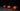 Drei orange Kürbisse auf dunklem Holz vor schwarzem Hintergrund – stimmungsvolle Halloween-Dekoration.